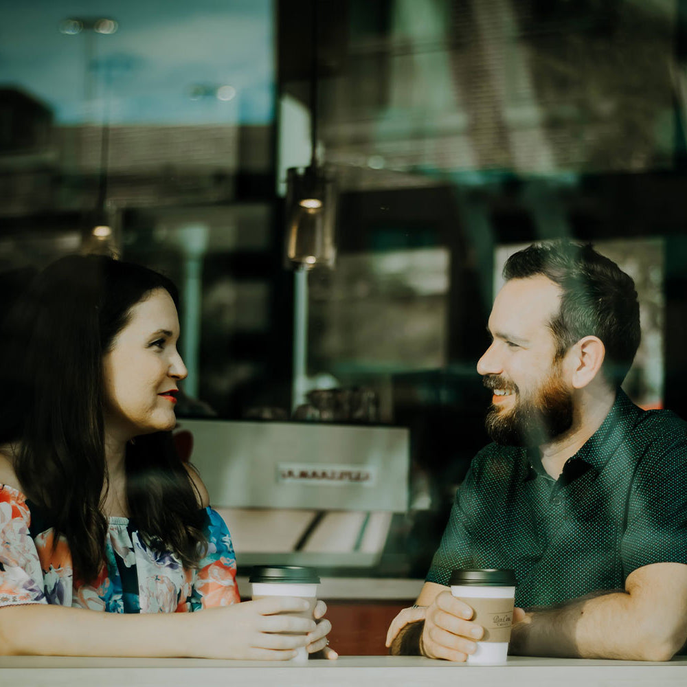 Man and lady in window at coffee shop, possibly being paid a compliment.