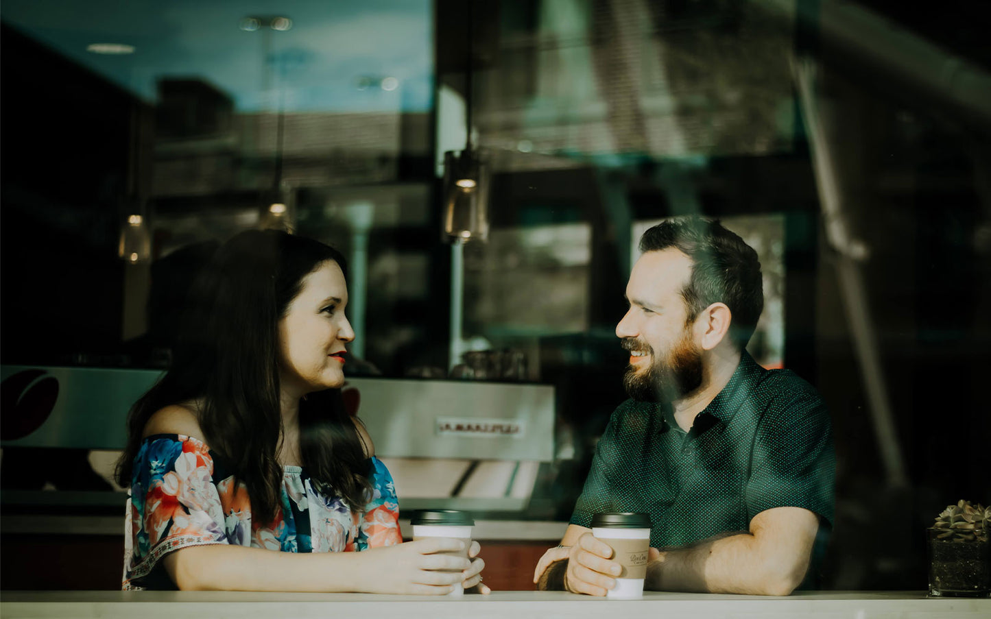 Man and lady in window at coffee shop, possibly being paid a compliment.